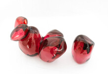 Clustered and sensuous oblong forms in translucent red glass have a smooth polished surface like the fruit that surrounds pomegranate seeds. Image 2