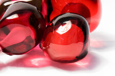 Clustered and sensuous oblong forms in translucent red glass have a smooth polished surface like the fruit that surrounds pomegranate seeds. Image 6