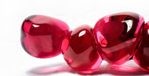 Clustered and sensuous oblong forms in translucent red glass have a smooth polished surface like the fruit that surrounds pomegranate seeds. Image 7