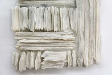 Wafers of cool white glass frit are layered and stacked in a curated wall relief by Cheryl Wilson Smith. Image 3