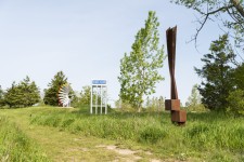 An elegantly curved column of corten steel appears to almost float in mid-air in this arresting outdoor sculpture by Claude Millette. Image 4