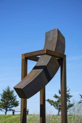 In this dynamic sculpture by artist Claude Millette corten steel is shaped into a right-angled curve and sits on a narrow stand.