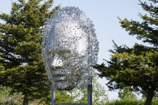 This contemporary wall sculpture of a mask is made out of metal. Image 4