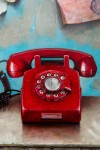 A bright red rotary phone sits on a turquoise-green cabinet, paper notes randomly taped to the wall, paint-peeling in this nostalgic trompe … Image 5