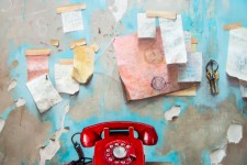 A bright red rotary phone sits on a turquoise-green cabinet, paper notes randomly taped to the wall, paint-peeling in this nostalgic trompe … Image 4