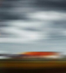 This captivating photo of the countryside—red roofed barn and cloudy sky was taken from a moving car by photographer Etienne Labbé.