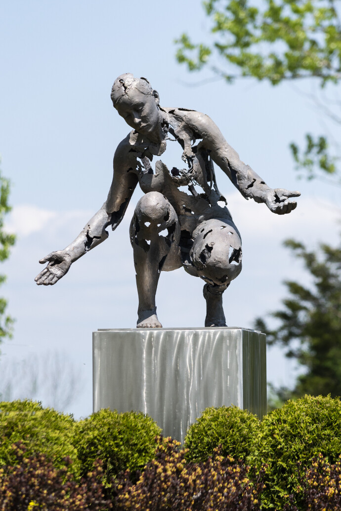 This figurative bronze and stainless steel outdoor sculpture of a female was created by a Canadian artist.