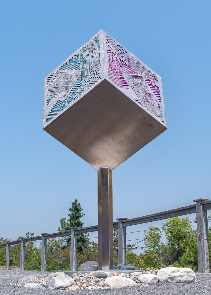 A stainless-steel cube is laser cut on three sides with the outline of a digital circuit board in this intriguing outdoor sculpture by Jake …