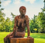 A seated female figure strikes a casual pose, body half turned in this imposing sculpture by American artist, Jason Kimes. Image 4