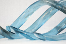 Four undulating lengths of smooth, translucent azure blue and charcoal glass move together in an elegant wave-like rhythm. Image 4