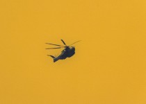 Helicopters hover over a lone figure stands on a scorched ground in this dramatic photo based image by Mark Bartkiw. Image 2