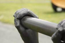 Like long arms, a set of two vertical copper pipes topped by bronze cast hands emerge from the ground. Image 4