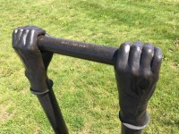 Like long arms, two vertical copper pipes topped by bronze cast hands emerge from the ground. Image 4