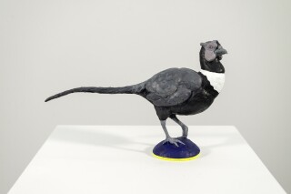 This tabletop indoor figurative sculpture of a bird is made of resin.