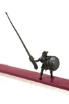 A bronze half-man, half dog figure holds a shield and brandishes a coffee stir stick as he ascends a steel pathway heading into the heavens,… Image 2