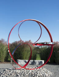 Four stainless steel rings, one side in poppy red, are curated into a elegant outdoor composition by Philippe Pallafray.