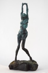 This female figure has her arms fully extended over her head as a dancer would stretch before performing.