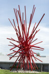 In an explosion of colour bright red painted steel poles crisscross one another in this dynamic abstract sculpture by Shayne Dark. Image 3