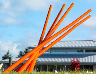 This contemporary orange-colored metal outdoor sculpture is the work of Shayne Dark.