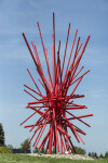 In an explosion of colour bright red painted steel poles crisscross one another in this dynamic abstract sculpture by Shayne Dark. Image 2