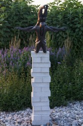 Two male figures, one balanced upside down on the back of another who kneels at a precipice, are cast in bronze.